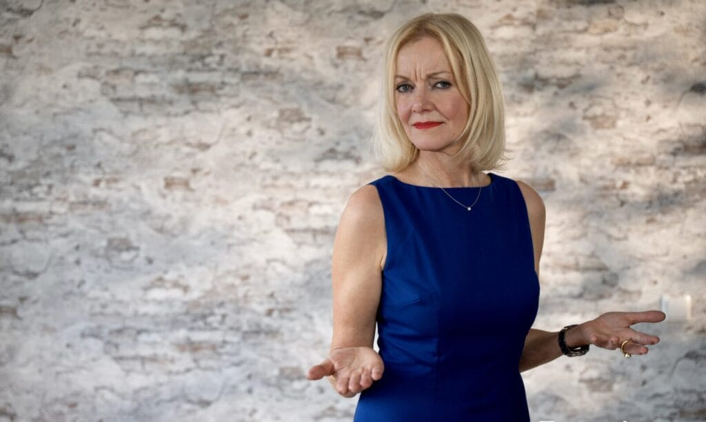 Frau in blauem Kleid vor Ziegelwand